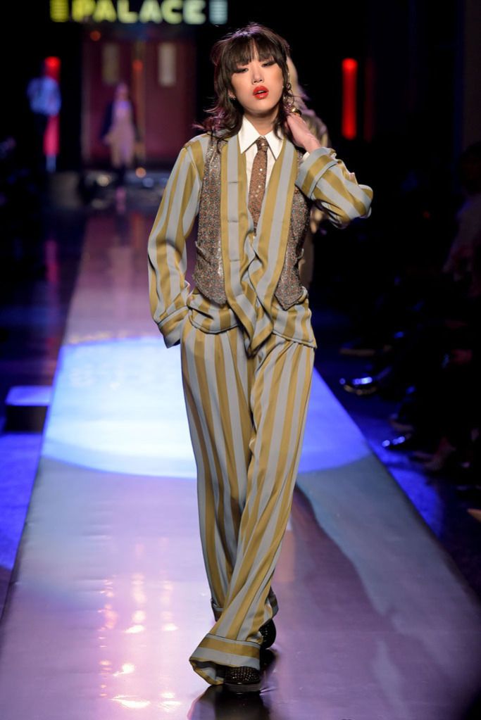 model habiller avec une cravate avec des brillants, elle porte une chemise blanche et un tuxedo railler de couleur jeune et vert gris.
